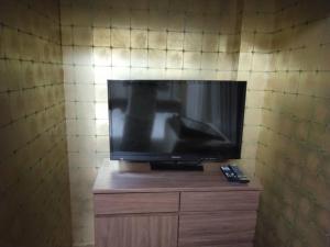 Ein Flachbildfernseher steht auf einem Holzschrank. in der Unterkunft Suiren in Nagoya