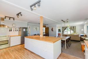 a kitchen with white cabinets and a dining room at Blizzard Bunny Lodge 43 Gippsland Street in Jindabyne