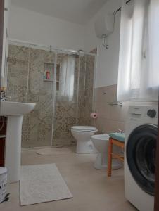 a bathroom with a shower toilet and a washing machine at Casa Locci in San Vito +24 photos