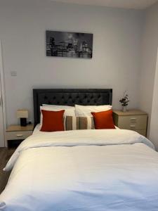 1 dormitorio con 1 cama blanca grande con almohadas de color naranja en Spencer Bridge House by AFL en Northampton