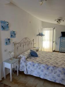 1 dormitorio con cama con colcha azul y mesa en B&B Kalinìkta, en Ascea