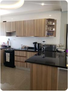a kitchen with a black counter top and wooden cabinets at The V Space in Lusaka