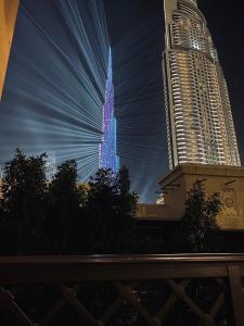 Wysoki wieżowiec świeci niebiesko w nocy w obiekcie Lux Burj views -Boulevard -Prime Location Downtown DUBAI w Dubaju