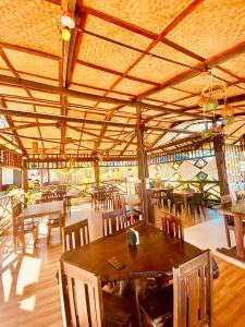 a restaurant with wooden tables and chairs and a wooden ceiling at Hill Myna Beach Cottages in Sabang