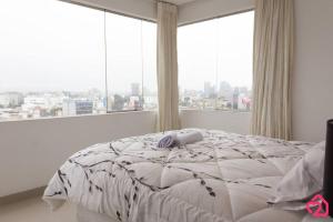 un letto bianco in una stanza con una grande finestra di Departamento con vista de Lima a Lima