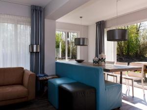a dining room with a blue couch and a table at Bungalow near De Alde Feanen with Boat in Earnewâld