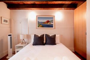 una camera da letto con un letto bianco con cuscini neri di Inner-city sanctuary with off-street parking a Hobart