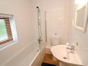 La salle de bains blanche est pourvue d'un lavabo et d'une douche. dans l'établissement Tregonning Lodge, à Helston