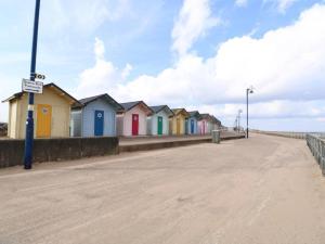 a row of colourful beach houses on the beach at Cozzzy Seaside Retreat in Mablethorpe