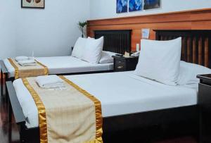 two beds in a hotel room with white sheets at RedDoorz at Nick Hotel Isabela 