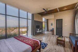 una camera con letto e ampie vetrate di Wabi Sabi Resort, Igatpuri a Igatpuri