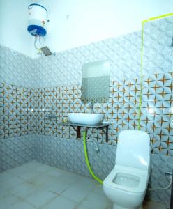 ein Badezimmer mit einem Waschbecken, einem WC und einem Spiegel in der Unterkunft Hotel Blossom in Lucknow