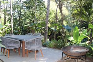a patio with a table and chairs and trees at The Moreporks Cottage in Ostend