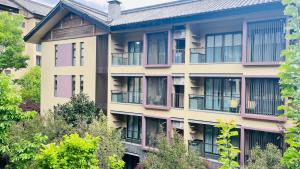 un immeuble d'appartements avec balcon et arbres dans l'établissement Argyle Resort Lijiang Tujing Shuhe Ancient Town, à Lijiang