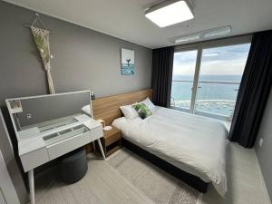 a bedroom with a bed with a desk and a window at The Gangneung Ocean Stay in Gangneung