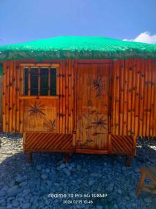 a wooden cabin with a green roof at Villa Rosita Peebles Beach in Surigao