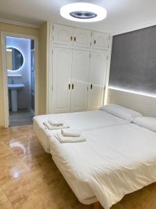 ベニドルムにあるApartamentos Carmelaのベッドルーム(大きな白いベッド1台、バスルーム付)