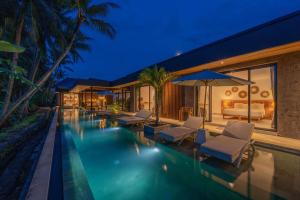 uma piscina com espreguiçadeiras e uma casa em Villa Surga - 4BR Heavenly Ricefields View Villa in Ubud em Ubud