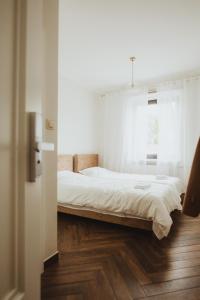 a bedroom with a bed with white sheets and a window at Apartamenty - Dom Hrabiny in Sieradz