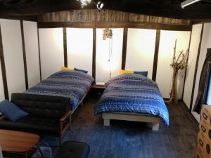 2 Betten in einem Zimmer mit Sofa in der Unterkunft sato no mori KURA - Vacation STAY 20504v in Nagano
