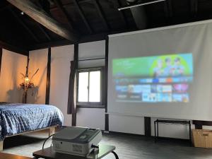 a projection screen in a room with a bed and a projector at sato no mori KURA - Vacation STAY 20504v in Nagano