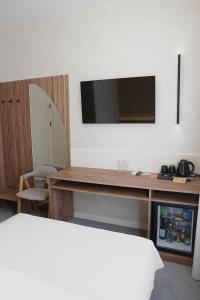 een kamer met een bureau en een televisie aan de muur bij Duboviy Gai Hotel in Vinnytsya