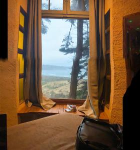 ein Schlafzimmer mit einem Fenster mit Blick auf einen Baum in der Unterkunft Hotel Boutique El Duende Mantagua in Quintero