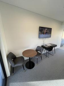 Habitación con mesa, sillas y TV. en Harden Country Club Motel, en Harden