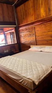 Bett in einem Zimmer mit Holzwänden in der Unterkunft nhà gỗ homestay nguyên văn in Hưng Lương