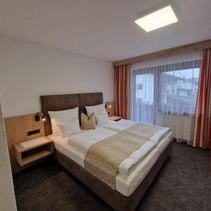 - une chambre avec un grand lit et une grande fenêtre dans l'établissement Gästehaus Burgi, à Fügen