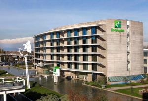 un edificio con un letrero junto a un río en Holiday Inn Santiago - Airport Terminal by IHG, en Santiago