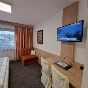 a hotel room with a table and a tv on the wall at Gästehaus Burgi in Fügen