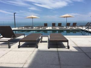 a pool with tables and chairs and umbrellas at Windsor Marapendi Hotel in Rio de Janeiro