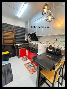 a kitchen with a black counter and red cabinets at Kpbc Homestay 3bilik in Jitra
