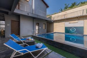 two lounge chairs and a swimming pool in front of a building at Wabi Sabi Resort, Igatpuri in Igatpuri