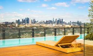 a chair on a balcony with a view of the city at Serenity 1br Flemington Balcony Pool Free Park in Melbourne