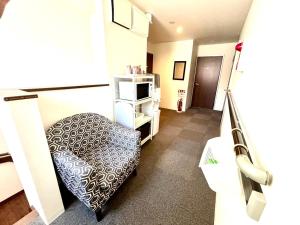 a room with a chair and a tv in it at GuestHouseえにし in Nishi-kujō-Toriiguchichō