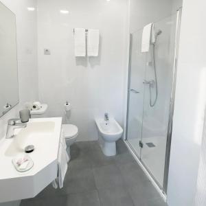 een witte badkamer met een toilet en een douche bij Hotel Portmán in Portman