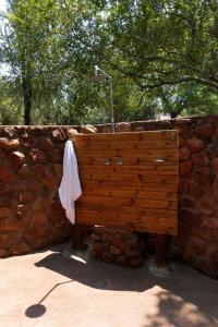 a wooden bench sitting next to a stone wall at Mologa River Lodge in Rust de Winter