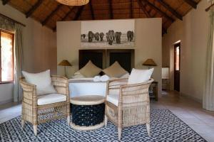 a living room with wicker chairs and a fireplace at Mologa River Lodge in Rust de Winter