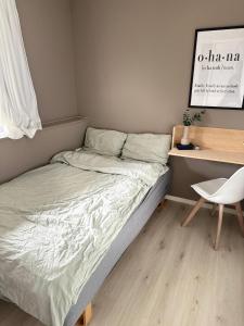 uma cama num quarto com uma secretária e uma cadeira em Koselig leilighet nær bussholdeplass og natur. em Tromsø