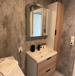 uma casa de banho com um lavatório e um espelho em Koselig leilighet nær bussholdeplass og natur. em Tromsø