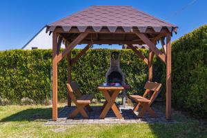 a wooden gazebo with two chairs and a table at Holiday Houses Alana & Alva with Garden by Renters in Międzywodzie