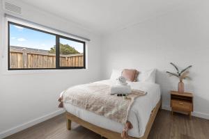 a white bedroom with a bed and a window at Rosebud by the Beach - Sea la Vie Four in Capel Sound