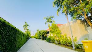 a sidewalk with palm trees and a building and a fence at summer pool villa in Laguna Phuket