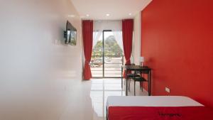 a red room with a bed and a table and a window at RedDoorz @ Aerial Hotel Los Baños in Los Baños
