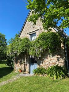 ein altes Steinhaus mit weißer Tür in der Unterkunft La Glycine in Landévant