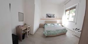 a bedroom with a bed and a desk and a window at Pratza Froria in Villasimius
