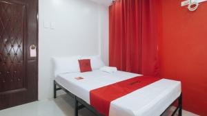 a small room with a bed with a red curtain at RedDoorz @ Aerial Hotel Los Baños in Los Baños