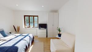 ein weißes Schlafzimmer mit einem Bett und einem Stuhl in der Unterkunft Ferienwohnung Burgau in Burgau